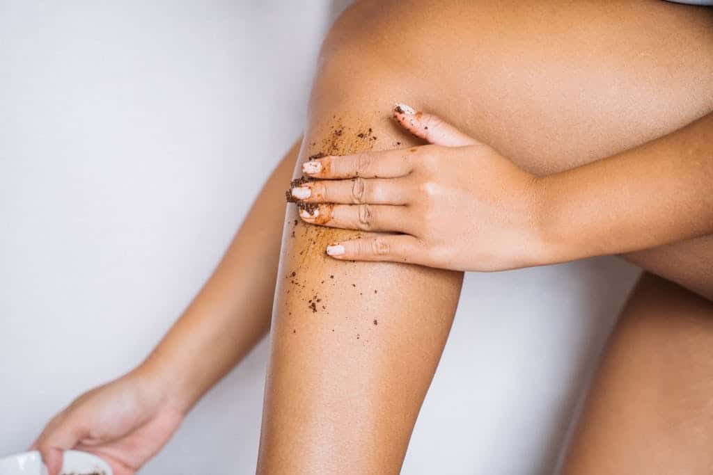 A Hand Applying Scrub on Her Leg