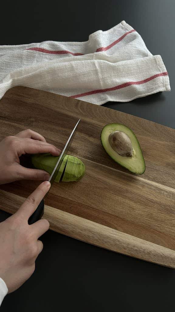 Person Cutting Avocado on Wooden Board